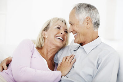 Senior couple laughing while looking at each other.