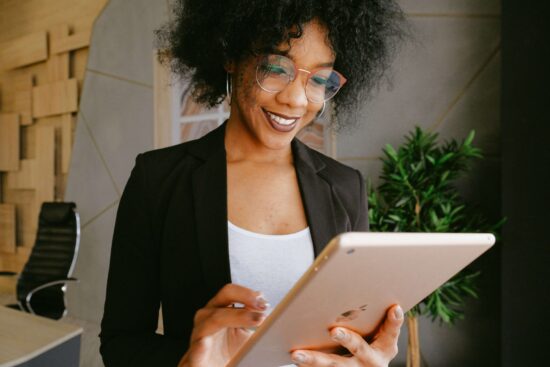 Woman in fashionable black blazer doing work on a tablet computer.
