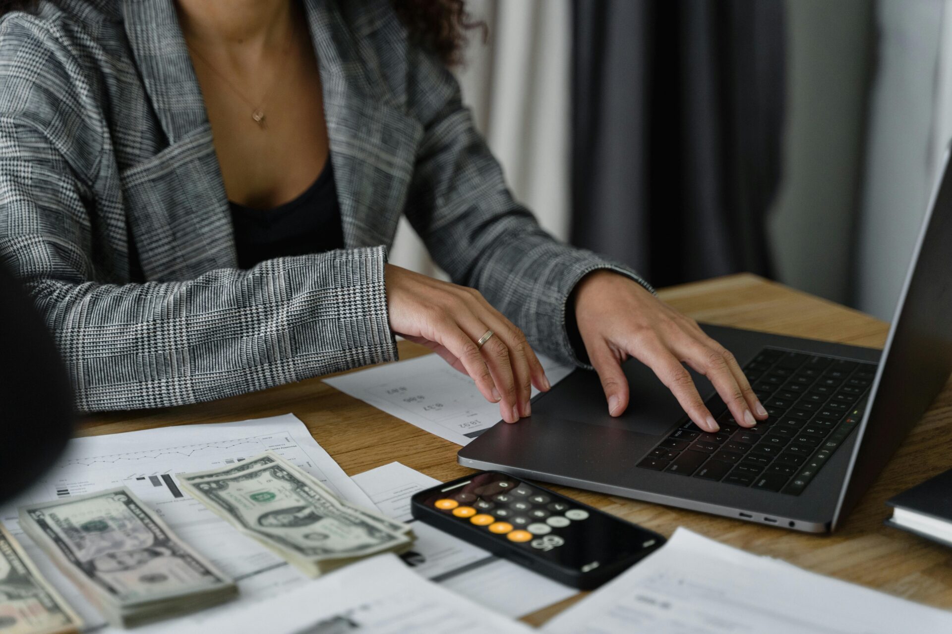 Woman on laptop with calculator and money