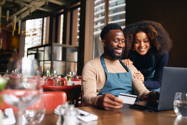 Business owners looking at laptop in restaurants paying bills through online banking