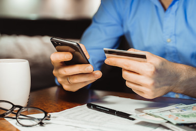 Man on mobile device checking bank account with debit card - choice plus checking