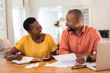 African American woman and man sitting at table looking a statements from Stillman Premier Checking Account,