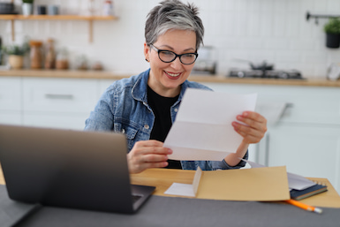 Middle aged woman sitting at table looking at Stillman checking account statement
